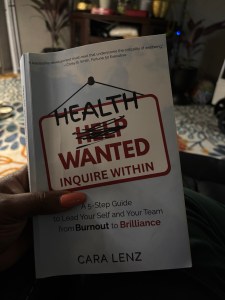 Health Wanted: Inquire Within by Cara Lenz held in hand